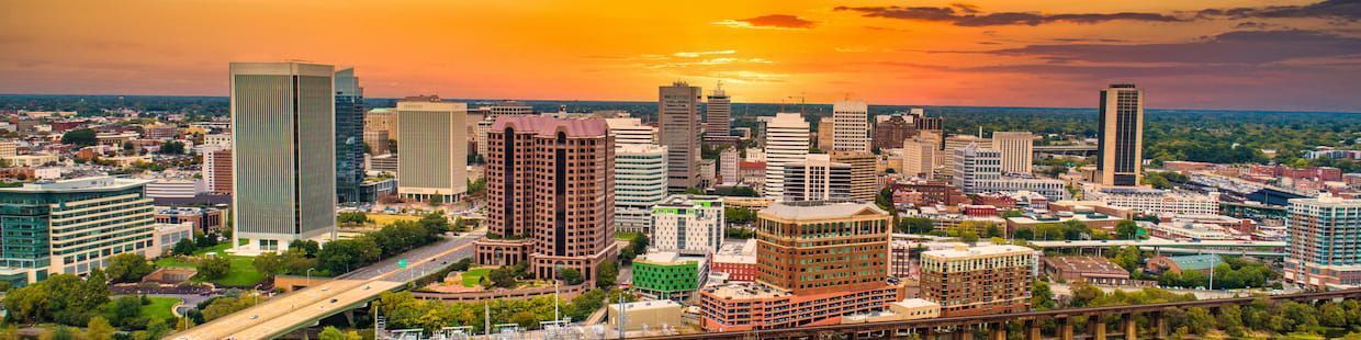 A vibrant Arizona city skyline at sunset, featuring modern skyscrapers and a mix of architectural styles. The sky is a blend of orange and yellow hues, casting a warm glow over the buildings and green spaces, reminiscent of the innovative spirit found in online programs for a Master's in Education.